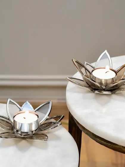 The lotus t-light holders in a nickel finish, placed on a marble surface. The cool tones of silver and white marble create a very serene and contemporary look.