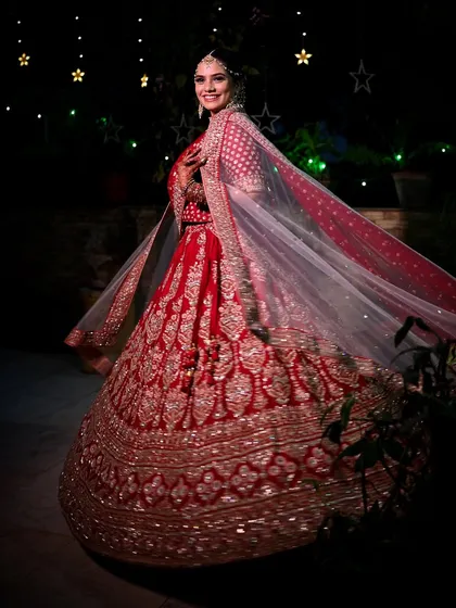 There is something magical about a bride's twirl. This shot captures the grace and grandeur of a traditional red lehenga under the stars, a perfect blend of cinematic flair and bridal joy for this Indian wedding.