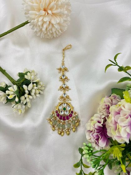 A delicate maang tikka with Kundan work and a combination of ruby and emerald stones. This is a perfect accessory for bridesmaids or for guests at festive events.