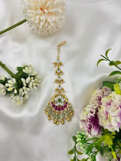 A beautiful standalone maang tikka with kundan, pearls, and a ruby-green motif.