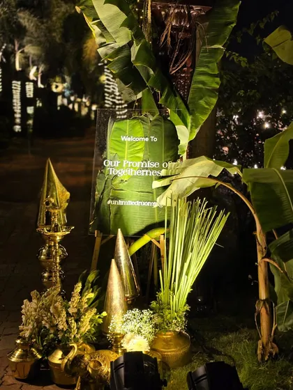 A traditional South Indian wedding welcome, using auspicious elements like banana leaf pillars, brass lamps, and fresh flowers to create a blessed and beautiful entrance.