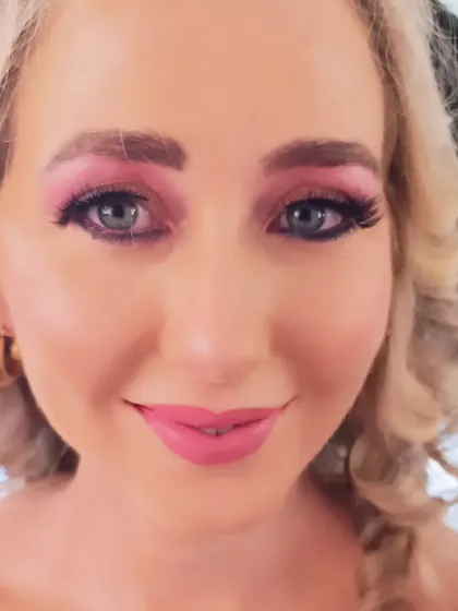 A full-face view of this colorful party makeup. The client's bright blue eyes pop against the pink eyeshadow.