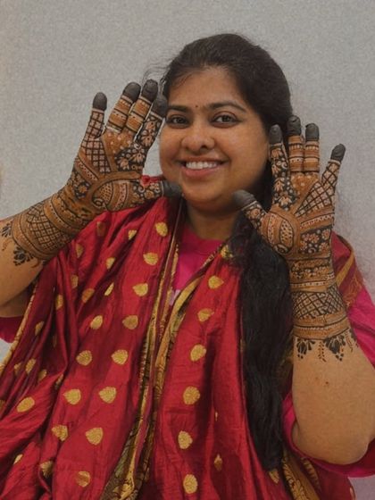 A happy smile from a guest showing off her full-hand traditional mehendi.