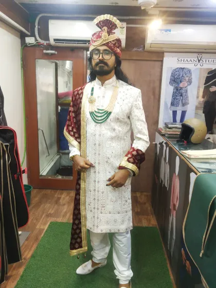 We design complete, head-to-toe groom ensembles. This client is ready for his wedding day in a custom white sherwani, complemented by a matching pagri (turban), a contrasting maroon dupatta, and traditional jewelry for a cohesive, royal look.