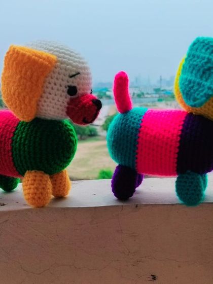 Two colorful dogs standing on a wall. These sausage dog style toys are made with bright, fun colors that children love.