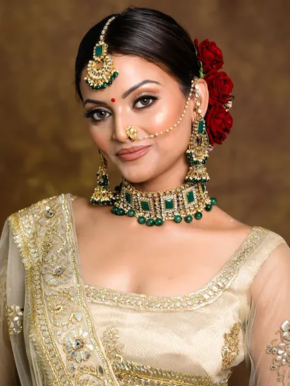 A beautiful, glowing bridal look. The makeup is neutral and elegant, letting the bride's natural beauty and her exquisite jewelry shine.
