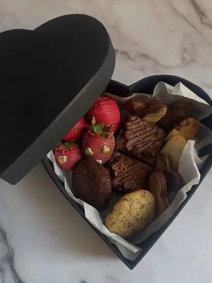 Gifting should be an experience. My heart-shaped Valentine's gift box is filled with an assortment of treats like chocolate-covered strawberries, fudgy brownies, and gourmet cookies.