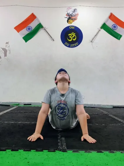 A student practices the cobra pose (Bhujangasana), which helps improve posture and spinal flexibility. We incorporate these asanas to keep our students' bodies healthy and mobile.