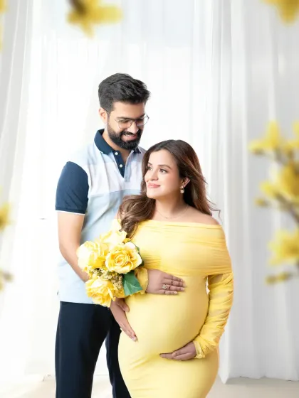 A bright and happy couple's portrait. The mother-to-be holds a bouquet of yellow flowers, perfectly matching her dress and the cheerful mood.