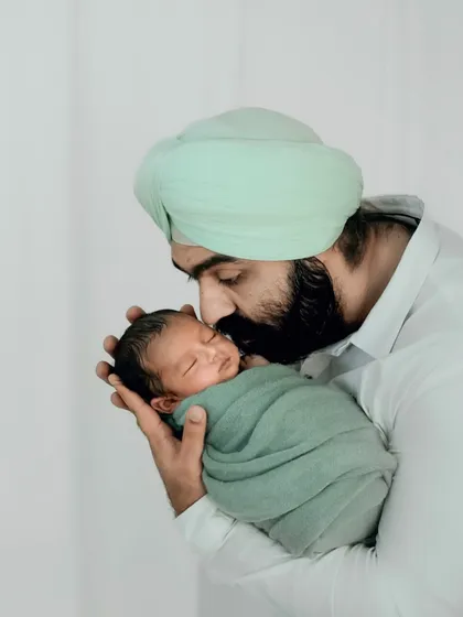 The gentle bond between a father and his newborn son. This portrait, with its soft lighting and tender hold, showcases the profound love that defines modern fatherhood.