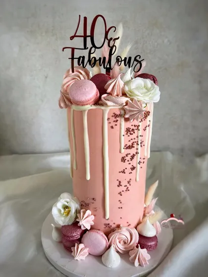 A rose gold beauty for a 40th birthday. This extra-tall 10-inch cake is adorned with a white chocolate drip, macarons, meringues, and flowers for a truly fabulous look.
