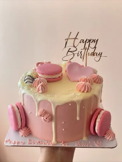 Another view of the pink chocolate drip cake, showing the "Happy Birthday" topper and delicate decorations.