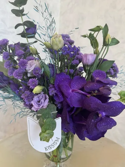 It's a Vanda orchid soirée. This simple yet stunning arrangement focuses on the deep, rich purple of the Vanda orchid, a truly exotic and luxurious bloom.