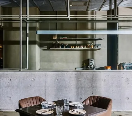 At the Evoo restaurant in Gurugram, the open kitchen is framed as a stage for culinary performance. The structure of exposed concrete and steel defines the space, creating an industrial aesthetic that complements the modern Italian dining experience.