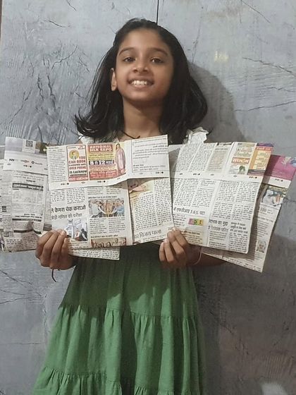 One of our young 'Reuse Rangers' proudly displays the newspaper bags she made in our workshop. These bags are then distributed to local shopkeepers to help reduce plastic use. We believe these kids are the real Planet Protectors.