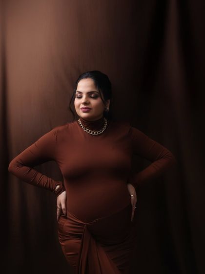 A moment of quiet contemplation. The rich brown tones and the mom-to-be's serene expression create a powerful and artistic portrait.