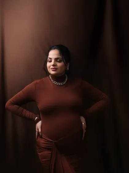 A moment of quiet contemplation. The rich brown tones and the mom-to-be's serene expression create a powerful and artistic portrait.