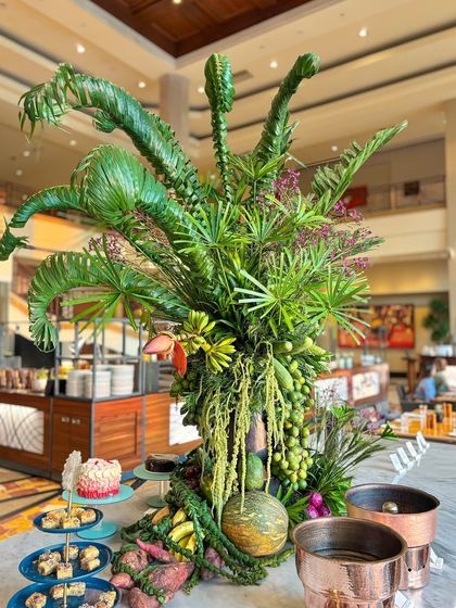 Another angle of the lush buffet decor, where sculptural, curled palm fronds add a whimsical and artistic touch to the composition.