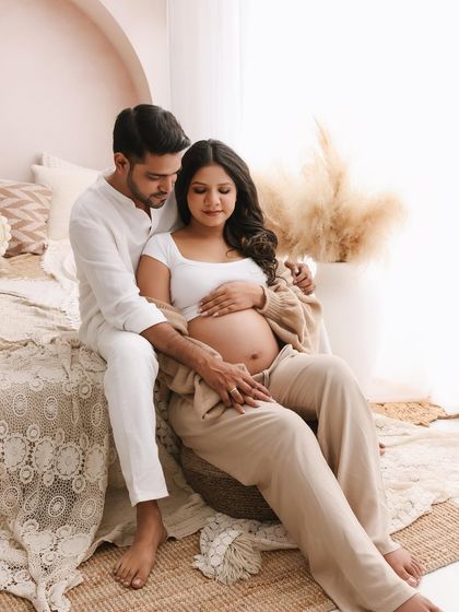 A portrait of quiet connection. His hand gently resting on hers over the baby bump is a simple yet powerful symbol of their shared journey into parenthood.