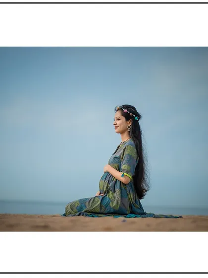 A serene portrait of a mom-to-be sitting on the sand, enjoying the calm of the beach.