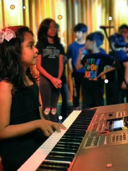 A young student takes her turn at the keyboard during a group session. We ensure every child gets hands-on time with each instrument.