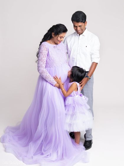 An intimate moment during a family maternity shoot. The daughter looks up at her mother's baby bump with so much love and curiosity, a perfect memory to cherish.