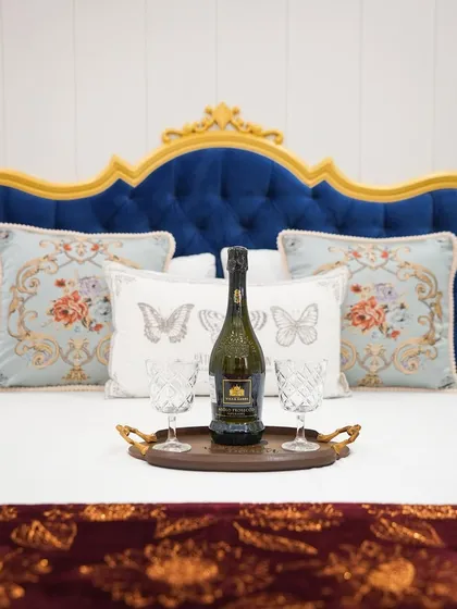 The details make the design. This shot of the ornate headboard and beautifully embroidered cushions captures the essence of the Bridgerton-inspired aesthetic.