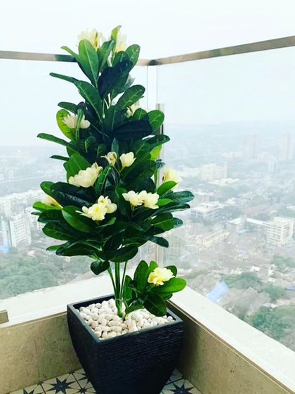 A beautiful artificial flowering tree in a pot on a high-rise balcony. This lets you enjoy the look of blooming flowers with a city view, no gardening required.