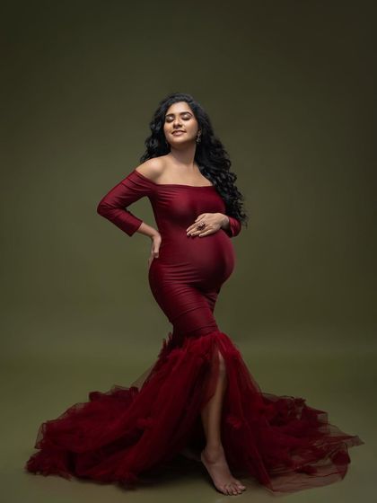 A beautiful, serene pose in the red gown, capturing the peaceful glow of pregnancy. The focus is entirely on her and the baby she is carrying.