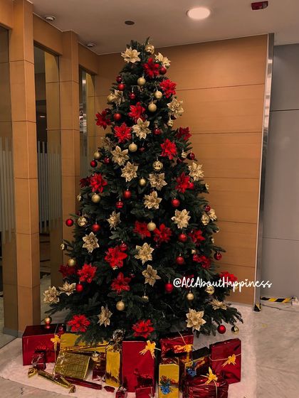 A full shot of the classic red and gold themed Christmas tree, complete with beautifully wrapped gift boxes at the base.