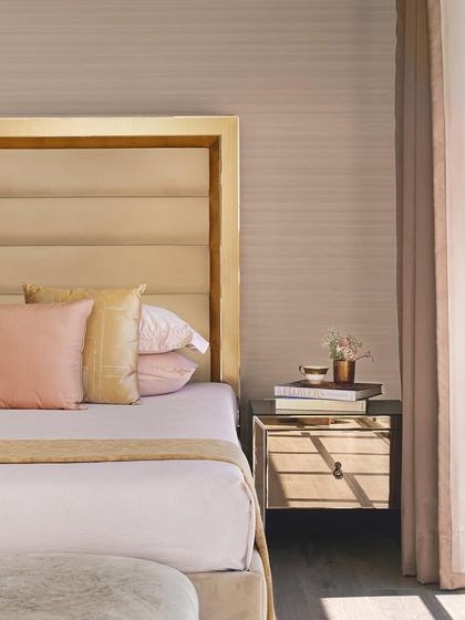 This guest bedroom in our 'DLH' project offers a peaceful sleep and a warm siesta. We used pastel shades and clean lines, from the headboard to the shadows of the French windows, to create a perfect home away from home, accentuated with books and fresh flowers.