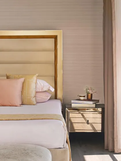 This guest bedroom in our 'DLH' project offers a peaceful sleep and a warm siesta. We used pastel shades and clean lines, from the headboard to the shadows of the French windows, to create a perfect home away from home, accentuated with books and fresh flowers.