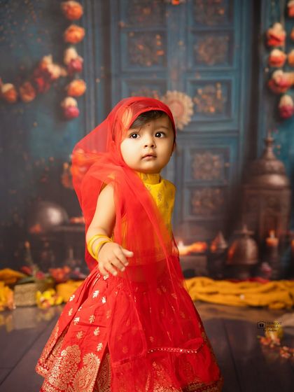 A little diva in festive vibes. This baby girl looks so precious in her red and yellow traditional outfit, ready for a celebration.