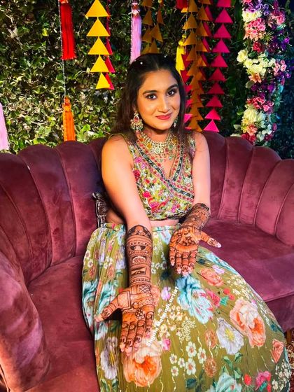 A happy client at her mehandi ceremony, set against a vibrant, colorful backdrop.