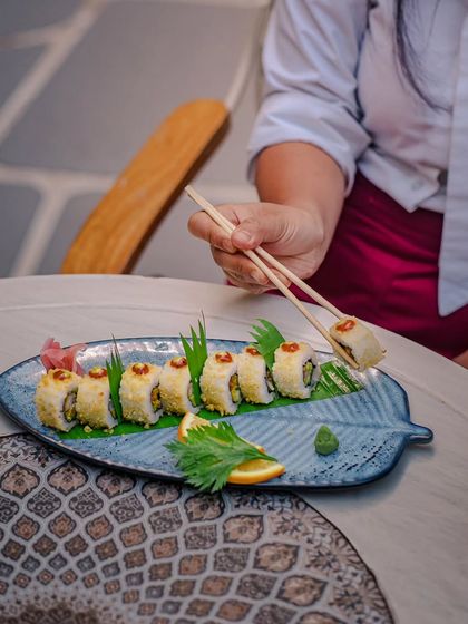 A guest enjoys a piece of our sushi, each roll a symphony of flavors, textures, and elegance.