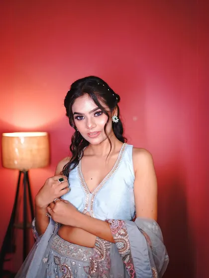 This shot highlights the modern, plunging neckline of the blouse and the delicate jewellery.