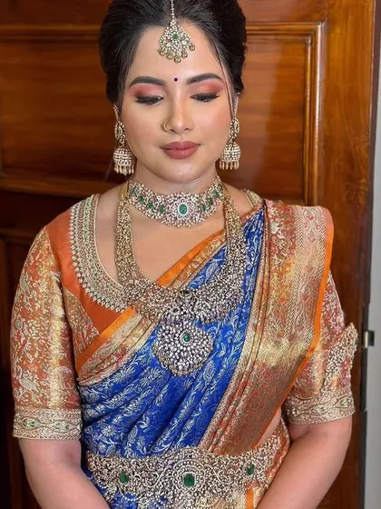 A bride in a rich blue and orange Kanchipuram saree. Her custom orange blouse is heavily embroidered with a traditional brocade pattern.