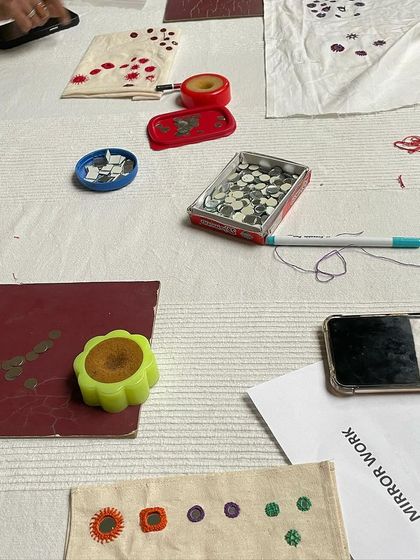 A flat lay of the materials used in our mirror work workshop: fabric samples, threads, a box of shisha mirrors, and pattern guides.