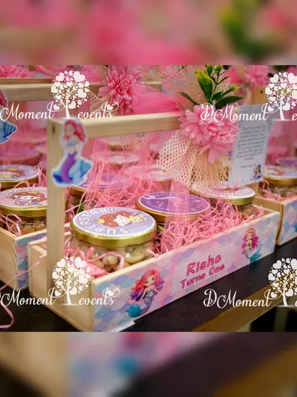 Thoughtfully curated return gifts for a mermaid-themed party, presented in personalized wooden baskets filled with themed goodies.