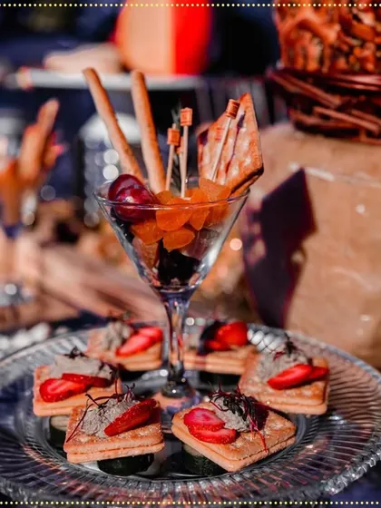 We transformed a wedding into a culinary journey with decadent appetizers. This display includes individual fruit and cracker cups alongside delicate strawberry and cream tartlets.