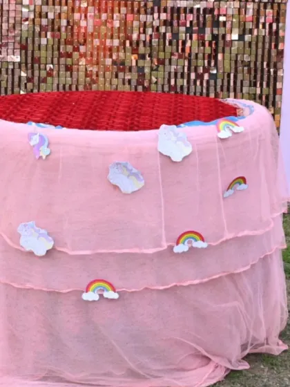 A close-up of the custom cake table, draped in pink tulle and decorated with cute cloud and rainbow cutouts.