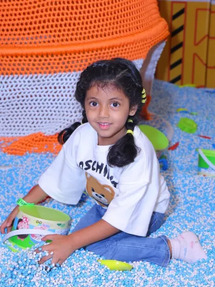 Pure happiness is a bucket and a ball pit. This little girl enjoys some creative playtime, surrounded by a sea of soft blue and white balls.
