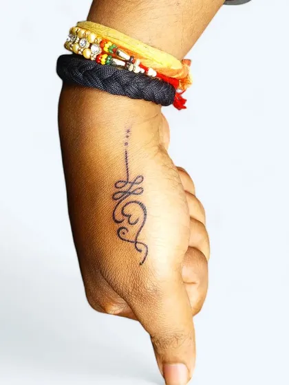 A minimalist Unalome tattoo on the thumb, symbolizing the journey to enlightenment. It's a small but powerful reminder of one's spiritual path.