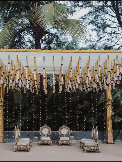 A closer look at a beautiful mandap designed for an outdoor ceremony. The structure is decorated with columns of yellow and white flowers, with hanging floral tassels and strings of lights creating a delicate and festive canopy.