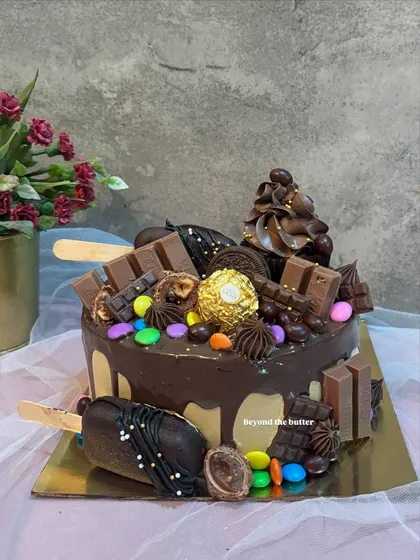 For the ultimate chocolate lover, I present this chocolate overload drip cake. It's a rich chocolate cake loaded with everything delicious: chocolate bars, Ferrero Rocher, colorful gems, and even chocolate cakesicles for an extra treat.