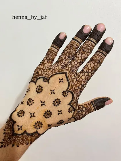 The back of the hand, showing a matching intricate design with a scalloped border and detailed finger work.