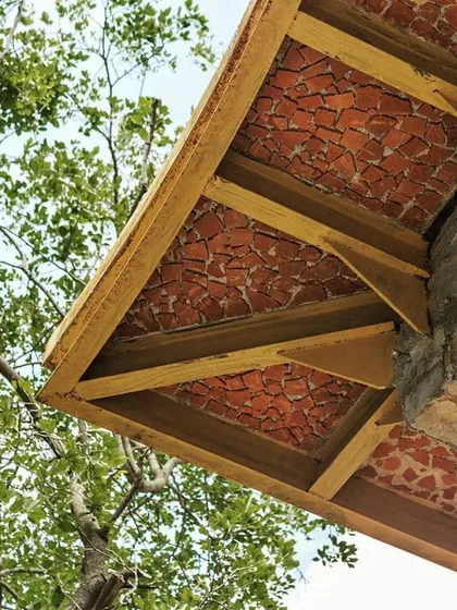 A closer look at a roof overhang reveals a ceiling crafted from broken clay tiles. This upcycling method creates a beautiful mosaic texture, demonstrating our commitment to finding creative, sustainable solutions in every detail.
