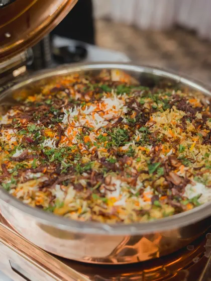 A large copper pot filled with my fragrant traditional Biryani. Topped with crispy fried onions and fresh herbs, it's a timeless classic that's always a centerpiece of the main course.