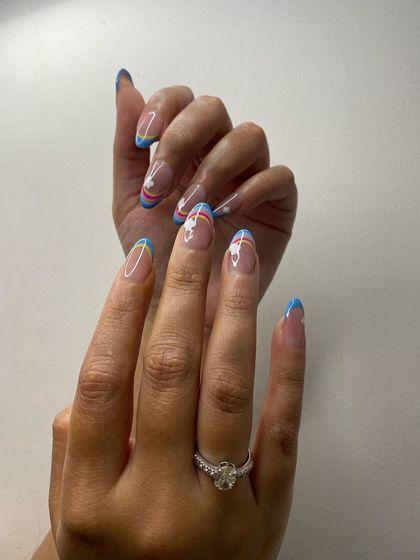 A playful and colorful design featuring a rainbow French tip with a small flower, perfect for a fun and cheerful look.