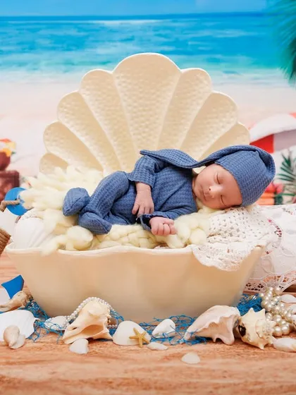 A wide shot of the 'pearl in a shell' newborn setup, with a beach backdrop and nautical props. A creative and beautiful way to announce a new arrival.